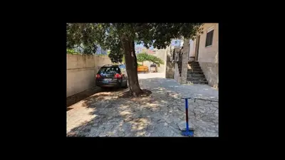 a car parked under a tree next to a building at Apartments Relax in Utjeha