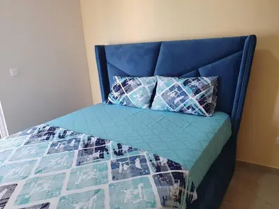 a bed with a blue headboard and pillows on it at Apartments Relax in Utjeha
