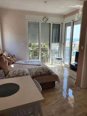 a bedroom with two beds and a living room with windows at Apartments Relax in Utjeha