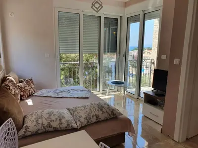 a living room with a couch and a tv and windows at Apartments Relax in Utjeha