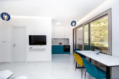 a kitchen with white cabinets and blue chairs at Aura Tower Aparments by In Property in Rafailovici