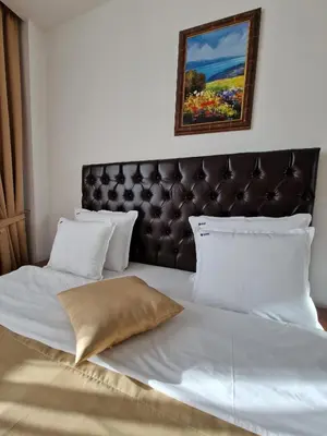 a large white bed with a leather headboard and pillows at Motel Celebic in Podgorica