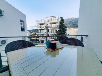 a glass table on a balcony with a view of a building at Mialex apartments in Dobra Voda