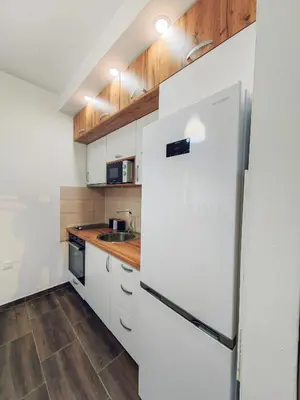 a kitchen with a white refrigerator and wooden cabinets at Mialex apartments in Dobra Voda