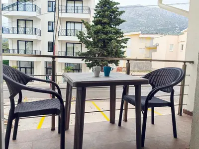 a table and two chairs on a balcony with a christmas tree at Mialex apartments in Dobra Voda