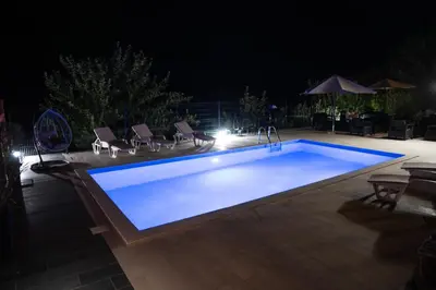 a swimming pool at night with chairs around it at Apartman Sedmica in Danilovgrad