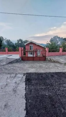a pink house with a gate in a parking lot at Apartman Sedmica in Danilovgrad