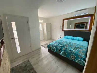 a bedroom with a bed and a mirror and a door at Apartman Sedmica in Danilovgrad