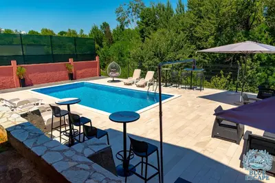 a swimming pool with chairs and a table and an umbrella at Apartman Sedmica in Danilovgrad
