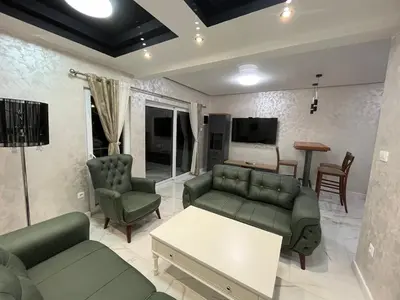 a living room with green couches and a tv at Cezar Apartments in Podgorica