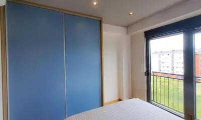 a bedroom with a blue closet and a large window at Stylish One Bedroom Apartment in Podgorica