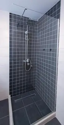 a bathroom with a shower with blue tiles at Stylish One Bedroom Apartment in Podgorica