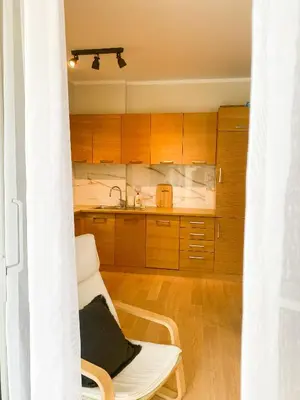 a kitchen with wooden cabinets and a white chair at Sunny apartment in Becici
