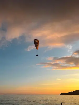 a person flying a kite in the sky over the ocean at Sunny apartment in Becici