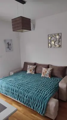 a bed with a green comforter in a room at Apartmani Stari Aerodrom in Podgorica