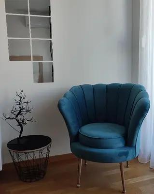 a blue chair in a living room with a table at Apartmani Stari Aerodrom in Podgorica