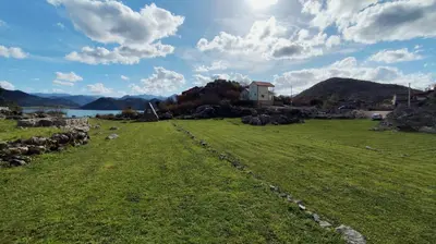 a grassy field with a house in the background at Bobija Village Skadar lake in Karuč