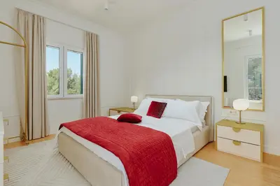 a white bedroom with a large bed with a red blanket at Vila Bellevue in Budva