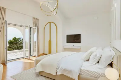 a white bedroom with a bed and a balcony at Vila Bellevue in Budva