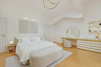 a white bedroom with a white bed and a mirror at Vila Bellevue in Budva