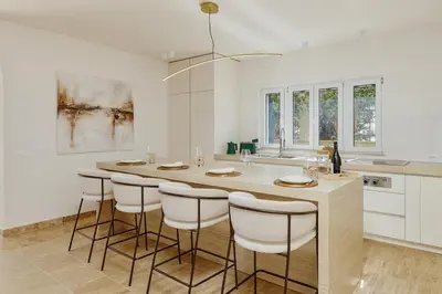 a white kitchen with a large island with bar stools at Vila Bellevue in Budva