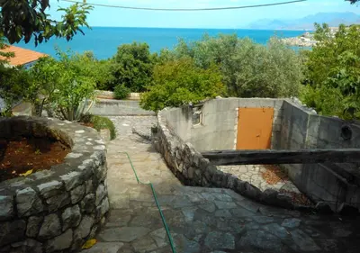 a stone retaining wall with a yellow door and the ocean at STONE HOUSE “MEDITERRANEO” in Bar