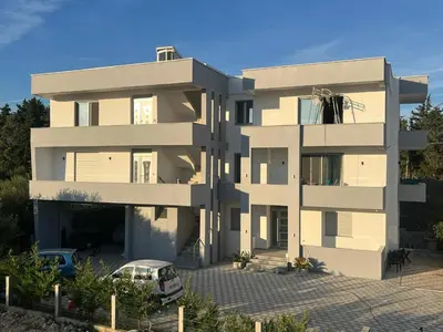 a building with a car parked in front of it at Apartments Bojku in Ulcinj