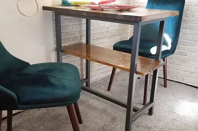 a table with two green chairs and a wooden bench at Sophie's Emerald Studio apartment in Podgorica