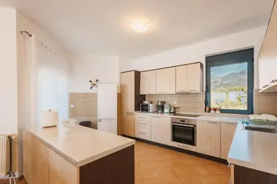 a kitchen with wooden cabinets and a large window at Orange Villa - 7 Bedrooms - 5 Star Location - Views - Pool in Dobra Voda