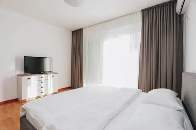 a bedroom with a bed and a tv and a window at Status-M Apartments Sunny Side in Becici