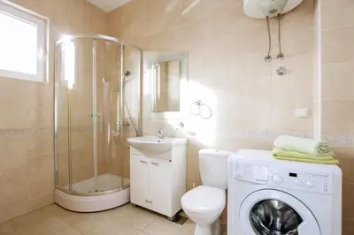 a bathroom with a shower toilet and a washing machine at Status-M Apartments Sunny Side in Becici
