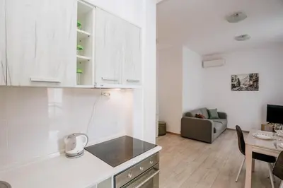 a kitchen with white cabinets and a living room at Status-M Apartments Przno in Pržno