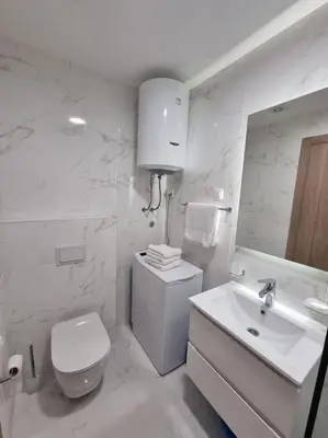 a white bathroom with a toilet and a sink at Master Quart modern apt. 27 in Podgorica
