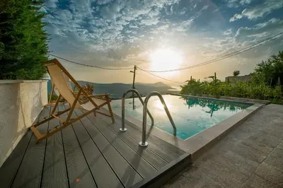 a chair sitting next to a swimming pool with the sunset at Villa Di Campagna in Kotor