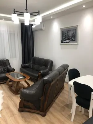 a living room with black leather furniture and a table at Apartments Long Beach in Ulcinj