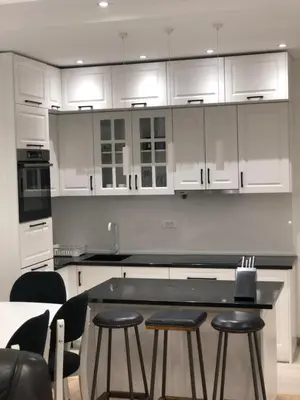 a kitchen with white cabinets and a table and stools at Apartments Long Beach in Ulcinj
