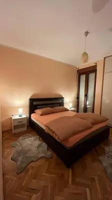 a bedroom with a bed and a wooden floor at Majdini Clock Tower Apartman in Podgorica