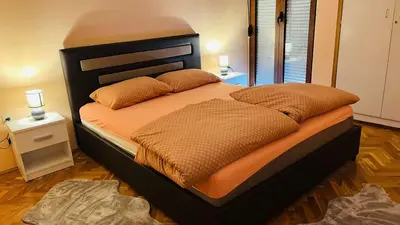 a bedroom with a large bed with orange sheets and pillows at Majdini Clock Tower Apartman in Podgorica