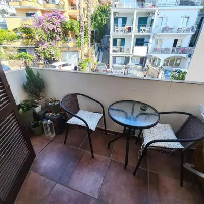 a table and two chairs on a balcony with buildings at Studio 75 meters to the sea in Rafailovici