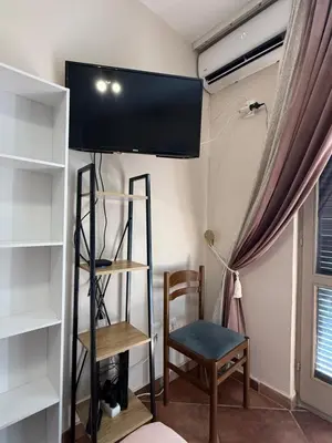 a room with a tv and a chair and a shelf at Studio 75 meters to the sea in Rafailovici