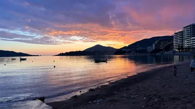 a sunset over a beach with boats in the water at Studio 75 meters to the sea in Rafailovici