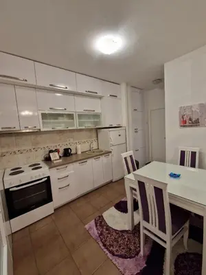 a kitchen with white cabinets and a table with chairs at Your place in Podgorica in Podgorica