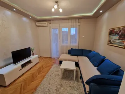 a living room with a blue couch and a tv at Your place in Podgorica in Podgorica