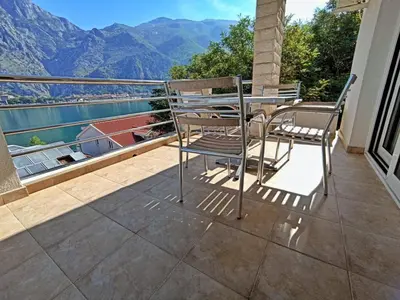 a table and chairs on a balcony with a view of the mountains at Apartment Kotor in Kotor