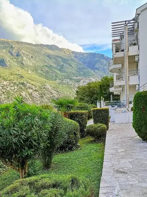 a building with bushes in front of a mountain at Apartment Kotor in Kotor