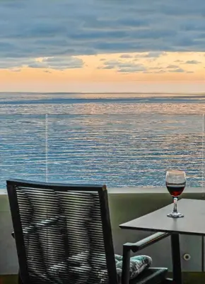 a glass of wine sitting on a table next to the ocean at Beachfront luxury apartment in Budva