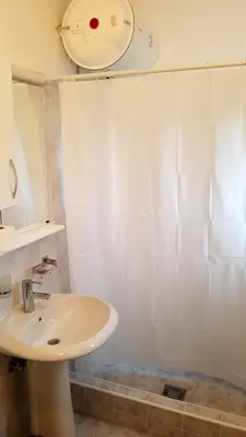 a white bathroom with a sink and a shower at Gregovic Apartments in Petrovac na Moru