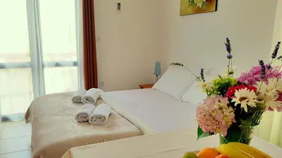 a bedroom with a bed with towels and a vase of flowers at Gregovic Apartments in Petrovac na Moru
