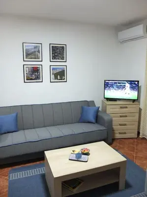 a living room with a couch and a table and a tv at Daydream Apartment in Podgorica in Podgorica
