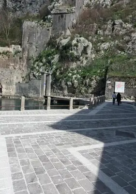 two people walking down a sidewalk near a mountain at Bond studios- Old town in Kotor
